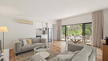 A modern living room with a sofa, a coffee table, and a dining area with a table and chairs.
