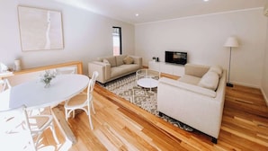 A modern living room with a dining table, two sofas, a TV, and a patterned rug. - Wren Studio - Private One-Bedroom Studio Nestled in Bushland (Yallingup)