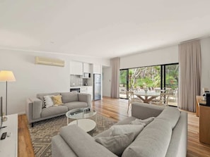A modern living room with a sofa, a coffee table, and a dining area with a table and chairs.