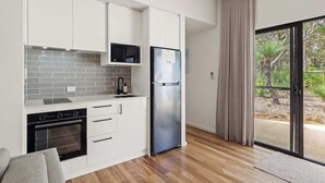 A modern kitchen with white cabinets, a stainless steel refrigerator, and a wooden floor. - Wren Studio - Private One-Bedroom Studio Nestled in Bushland (Yallingup)