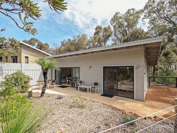A modern two-story house with a patio, sliding glass doors, and a small garden.