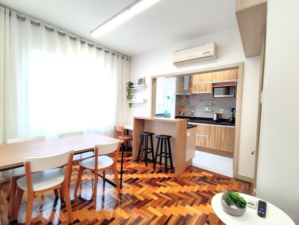 Une cuisine compacte équipée d’un four à micro-ondes, d’une cuisinière et de tabourets de bar.