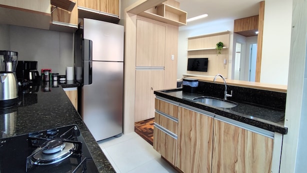 Eine moderne Küche mit einem Edelstahl-Kühlschrank, einem Gasherd und Holzschränken.
