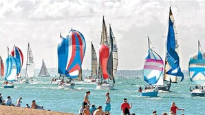 Une plage où l’on peut voir de nombreux voiliers et des gens se détendre sur le sable.