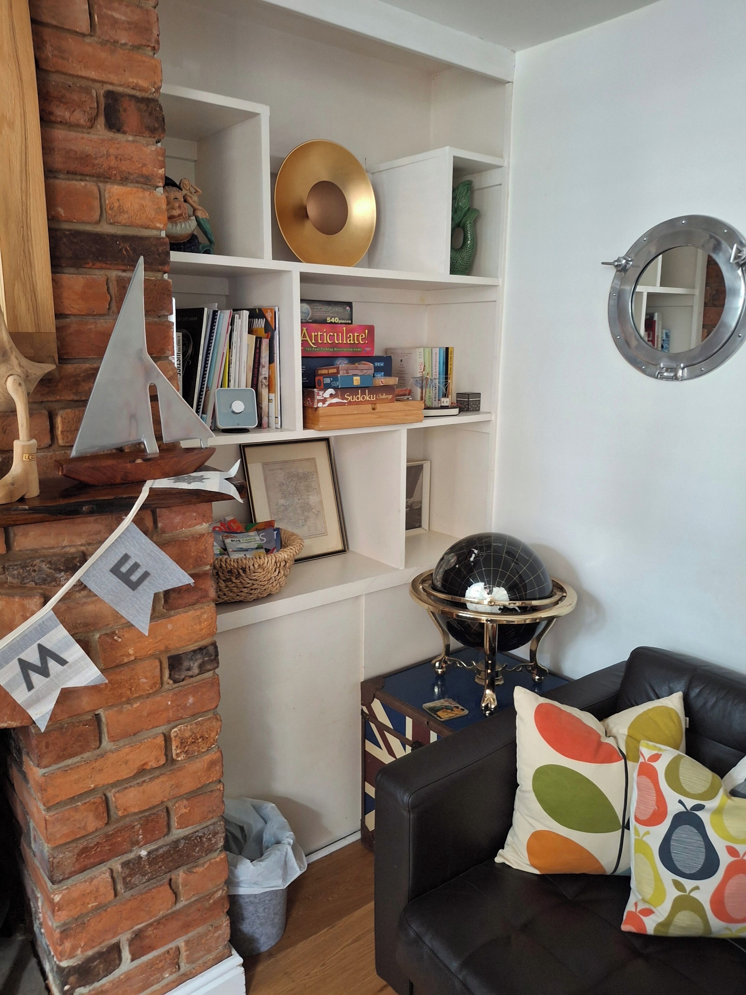 Un soggiorno con parete in mattoni, un divano in pelle nera, un globo e delle librerie.