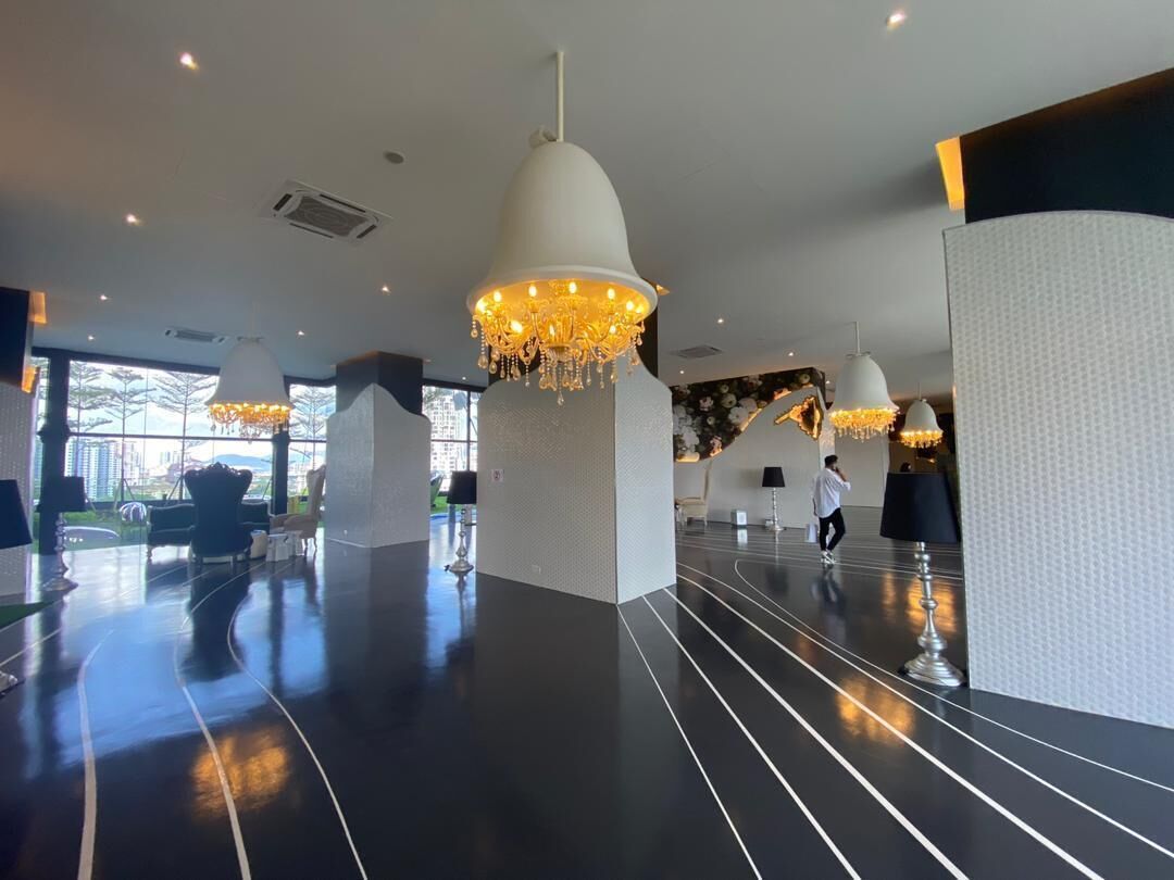 A spacious lobby with modern chandeliers, a polished black floor, and a view of the city through large windows.