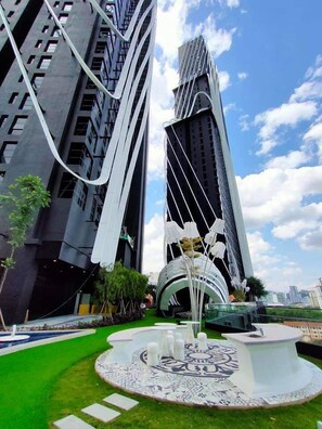 A modern building with a unique architectural design, featuring a circular fountain and a patterned walkway in the foreground. - Arte Mont Kiara By Autumn Suites (Kuala Lumpur)