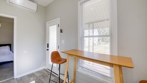 Una habitación con una mesa de madera, dos sillas, una puerta con cerradura y una ventana con persianas.