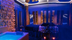 Un spa lujoso con pared de piedra, un jacuzzi y una mesa de masajes con velas.