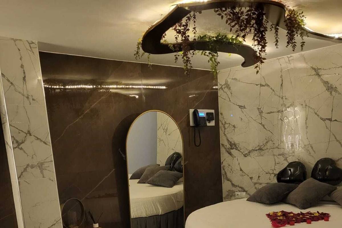 Un dormitorio con una cama grande, un pequeño rincón de descanso y un espejo.