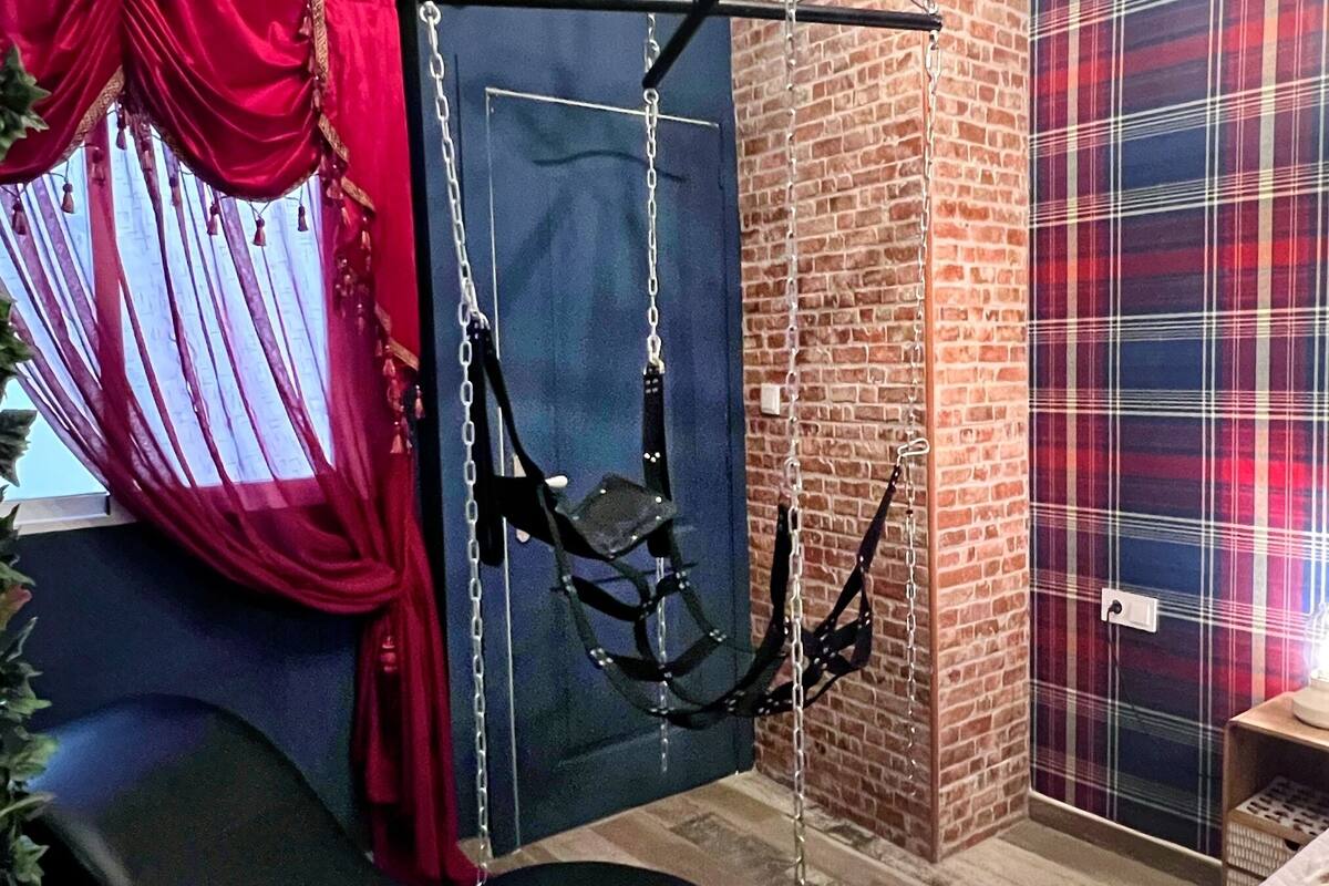 Una habitación con una hamaca colgante, un muro de ladrillo y un papel tapiz de cuadros.