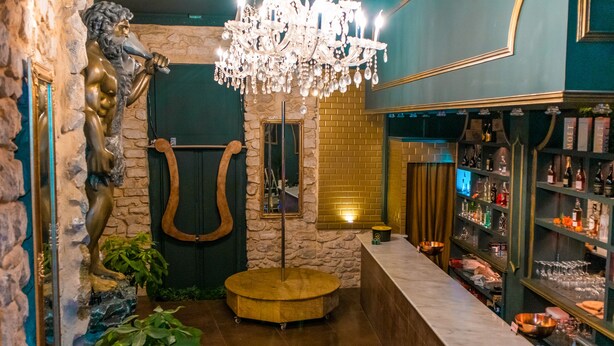 Zona de bar con candelabro, pared de piedra y mostrador de madera.