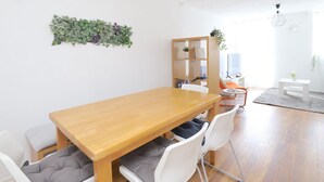 Ein moderner Essbereich mit einem Holztisch, weißen Stühlen und einem Bücherregal.