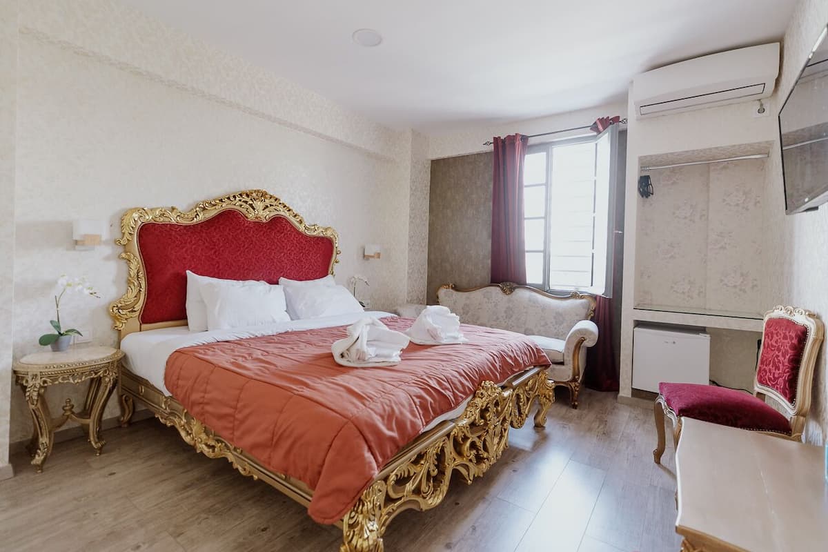 Un dormitorio amplio con una cama grande, una mesita de noche, una silla y un escritorio.