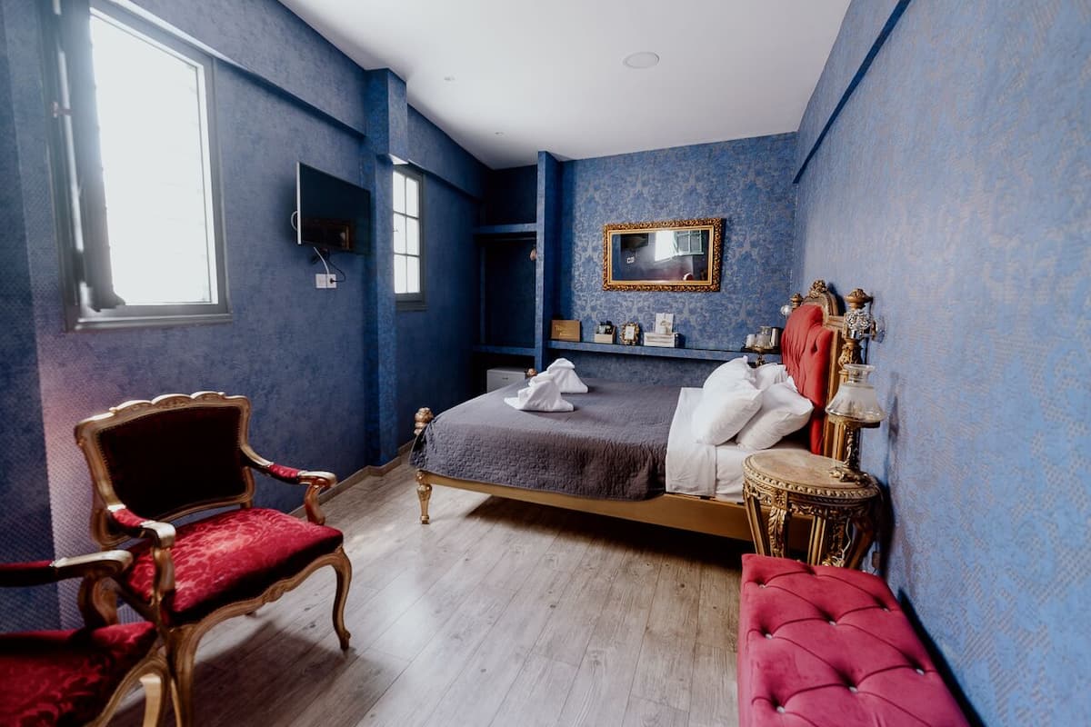 Un dormitorio con cama, una silla, una mesa y un espejo.