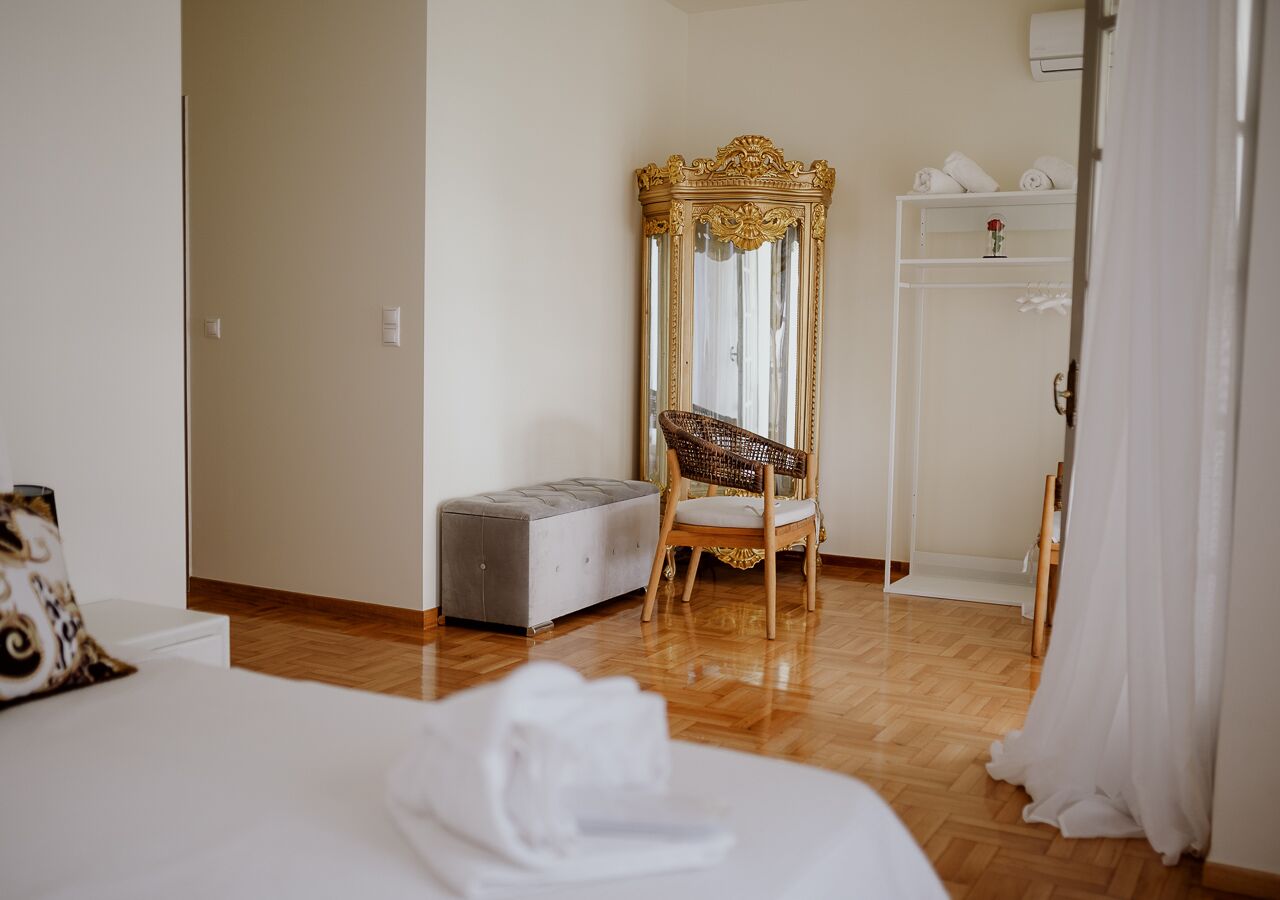 A hotel room with a bed, a vanity with a mirror, a chair, and a wardrobe.