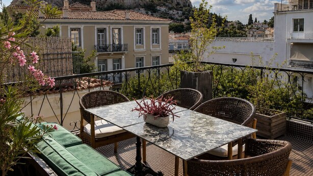 Una terraza con mobiliario de mimbre, una mesa y vistas a ruinas antiguas.