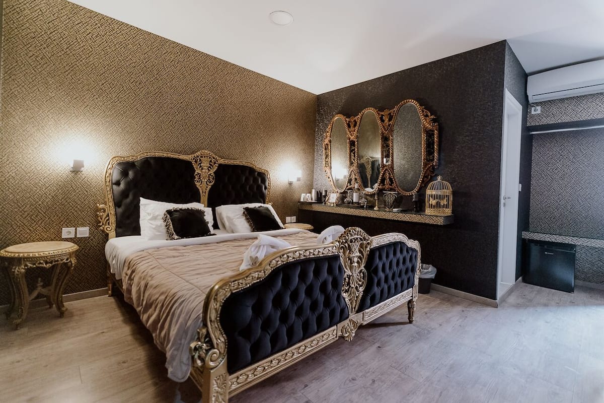 Un dormitorio lujoso con una cama grande, un cabecero ornamentado y una pared oscura con un diseño geométrico.