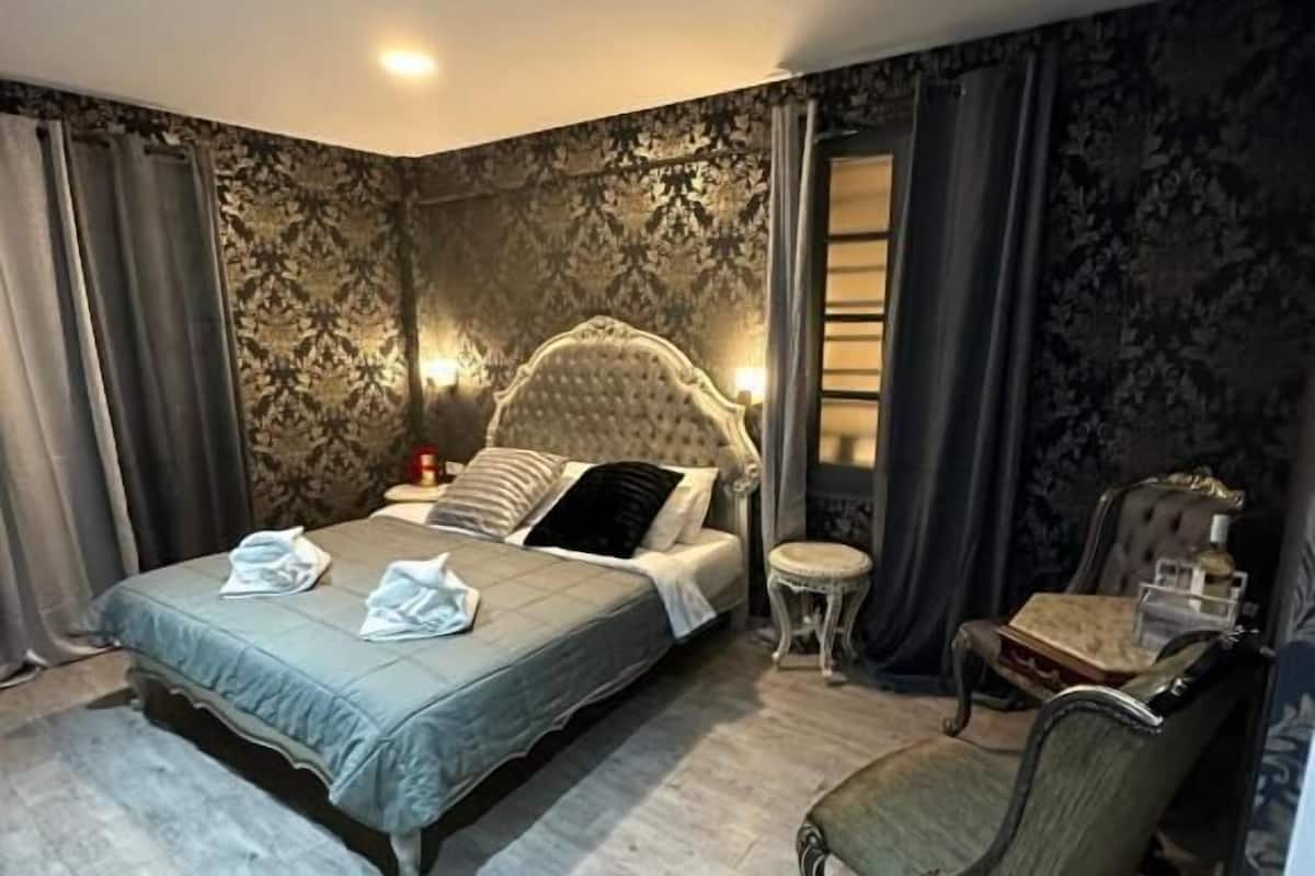 Un dormitorio con cama, una silla y una mesita.