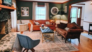 A cozy living room with a fireplace, a sofa set, a coffee table, and a stone accent wall. - Stunning Mountain Views with Hot Tub & 2 King Suites! Private & Peaceful. (Robbinsville)