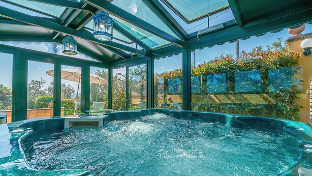 Un área con jacuzzi, envuelta en vidrio, con vistas despejadas del jardín y el cielo circundantes.