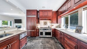 Enjoy cooking in this well-lit kitchen with a large island and sink, stainless steel range, and dark cabinetry.