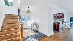 Stunning interior with a grand staircase, modern chandelier, and stylish kitchen area.