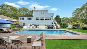 Une maison moderne à deux étages dotée d’une piscine, d’un espace salon extérieur et d’un patio couvert.