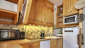 Una cocina compacta con armarios de madera, microondas, hervidor y lavavajillas.