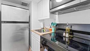 A kitchen with a stainless steel refrigerator, a microwave, and an induction cooktop. - Central Hyde Park studio close to UT, Moody Center (Austin)