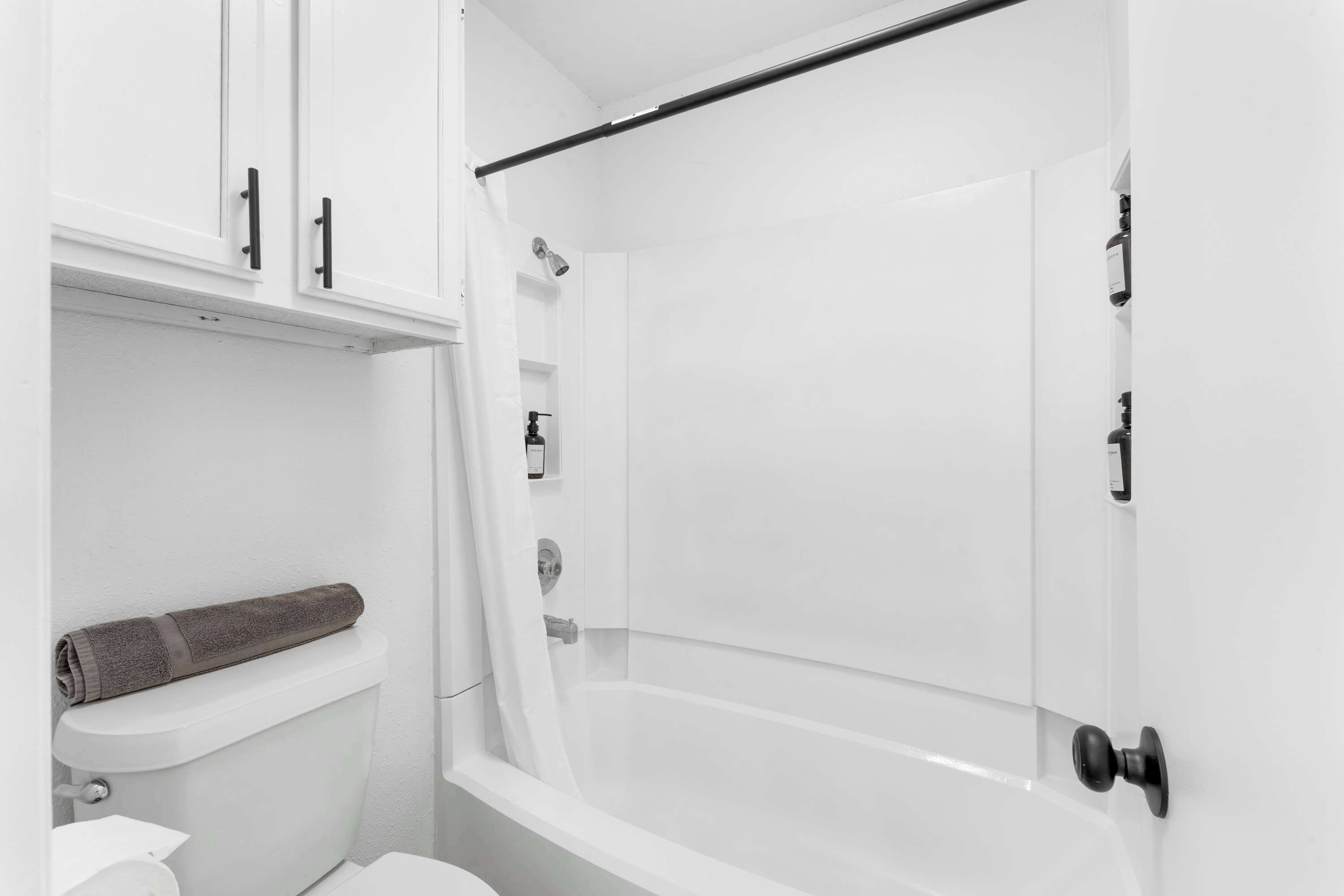 A bathroom with a toilet, a shower, and a towel rack.