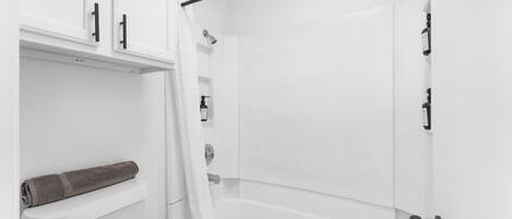 A bathroom with a toilet, a shower, and a towel rack.