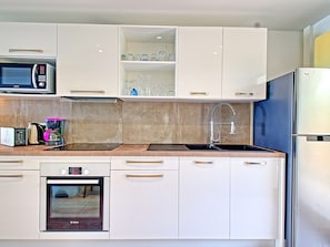 A modern kitchen with white cabinets, a Bosch oven, a coffee maker, and a microwave.