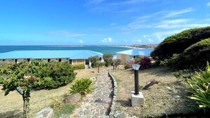A resort with a clear view of the ocean, a stone pathway, and a well-maintained garden.