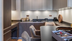 A modern kitchen with built-in cabinets, a central island with seating, and a coffee machine. - New 86m² in Courchevel 1850 - Ski-in/Ski-out, for 4 adults and 2 kids (Courchevel 1850)