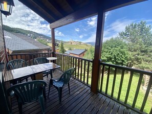 Enjoy a serene view of the surrounding countryside from this outdoor deck with a table and chairs.
