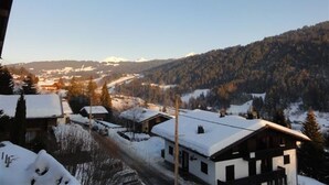 En snötäckt by med traditionella trähus och en fri utsikt över de omgivande bergen.
