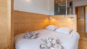 A modern bedroom with wooden paneling, a large bed with towels arranged in a bow shape, and a mirror above the bed. - Stunning 5-room duplex, 10 people, panoramic view, direct ski access, Avoriaz (Avoriaz)