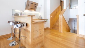 A modern kitchen with wooden cabinetry, a built-in microwave, and a bar stool with a cow print design. - Stunning 5-room duplex, 10 people, panoramic view, direct ski access, Avoriaz (Avoriaz)