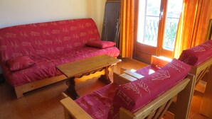 A cozy living room with a red sofa, wooden coffee table, and two wooden chairs.