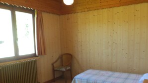 A room with two beds, a chair, a window, and a radiator.