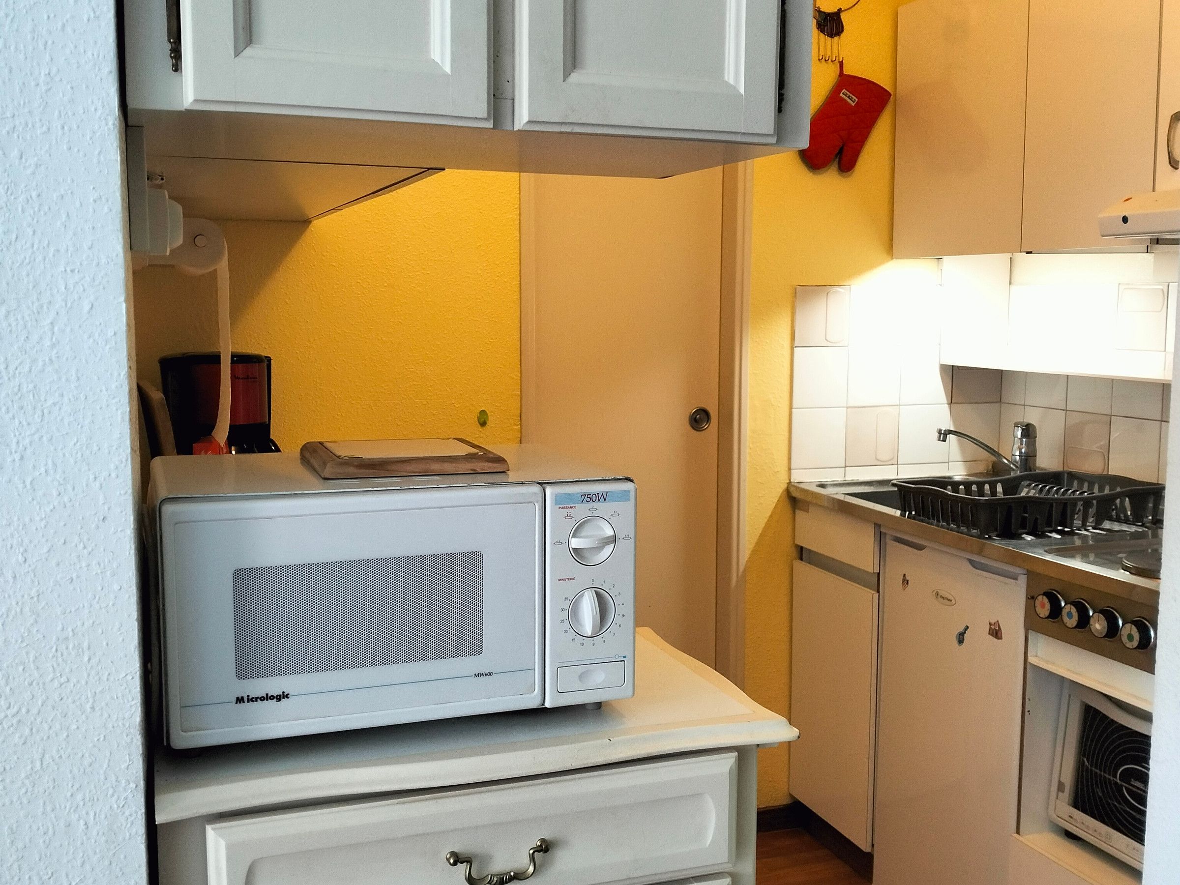 A compact kitchen with a microwave on a counter, a stove, and a sink.
