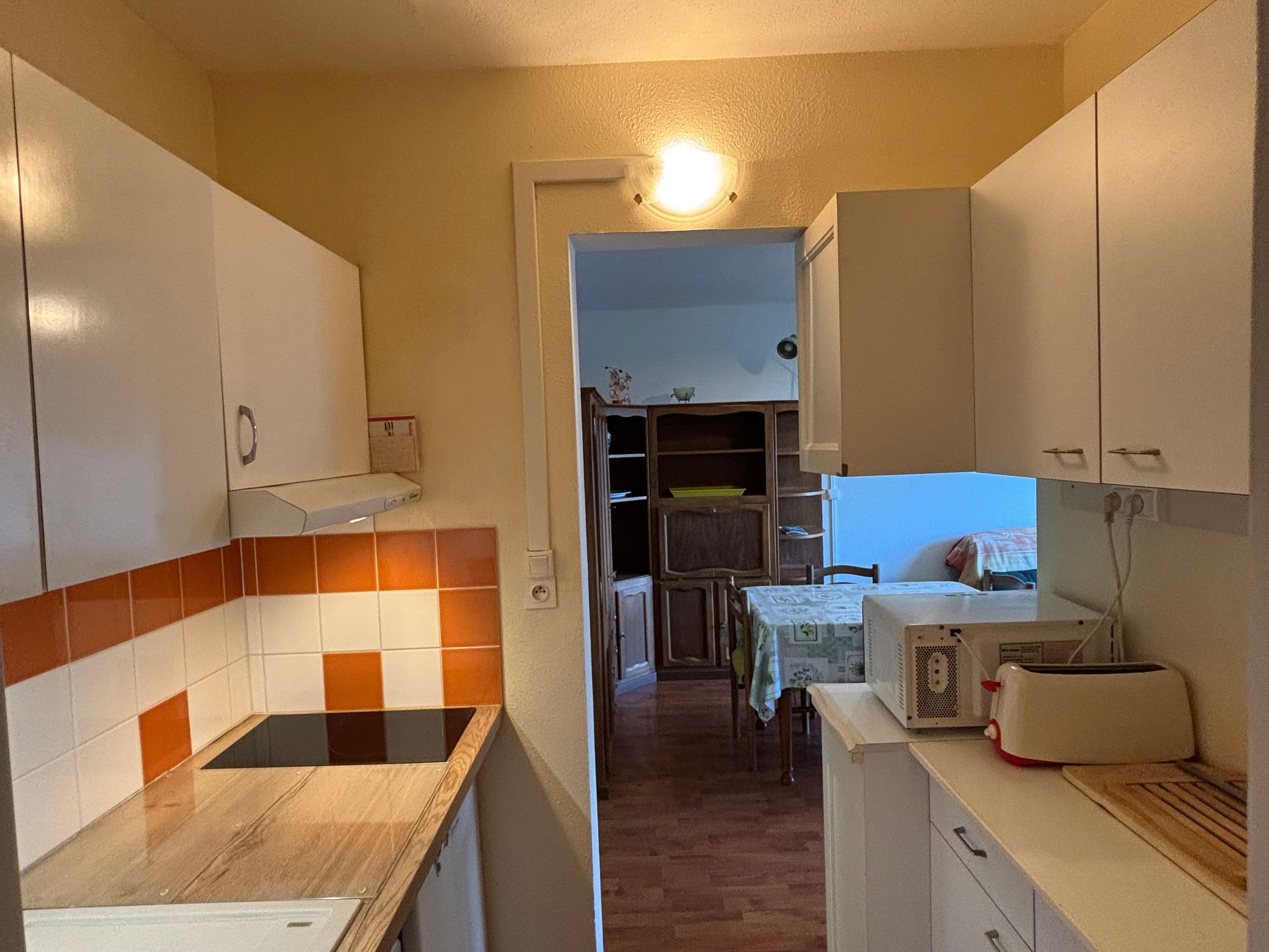 A compact kitchen with white cabinets, a wooden countertop, and a microwave.