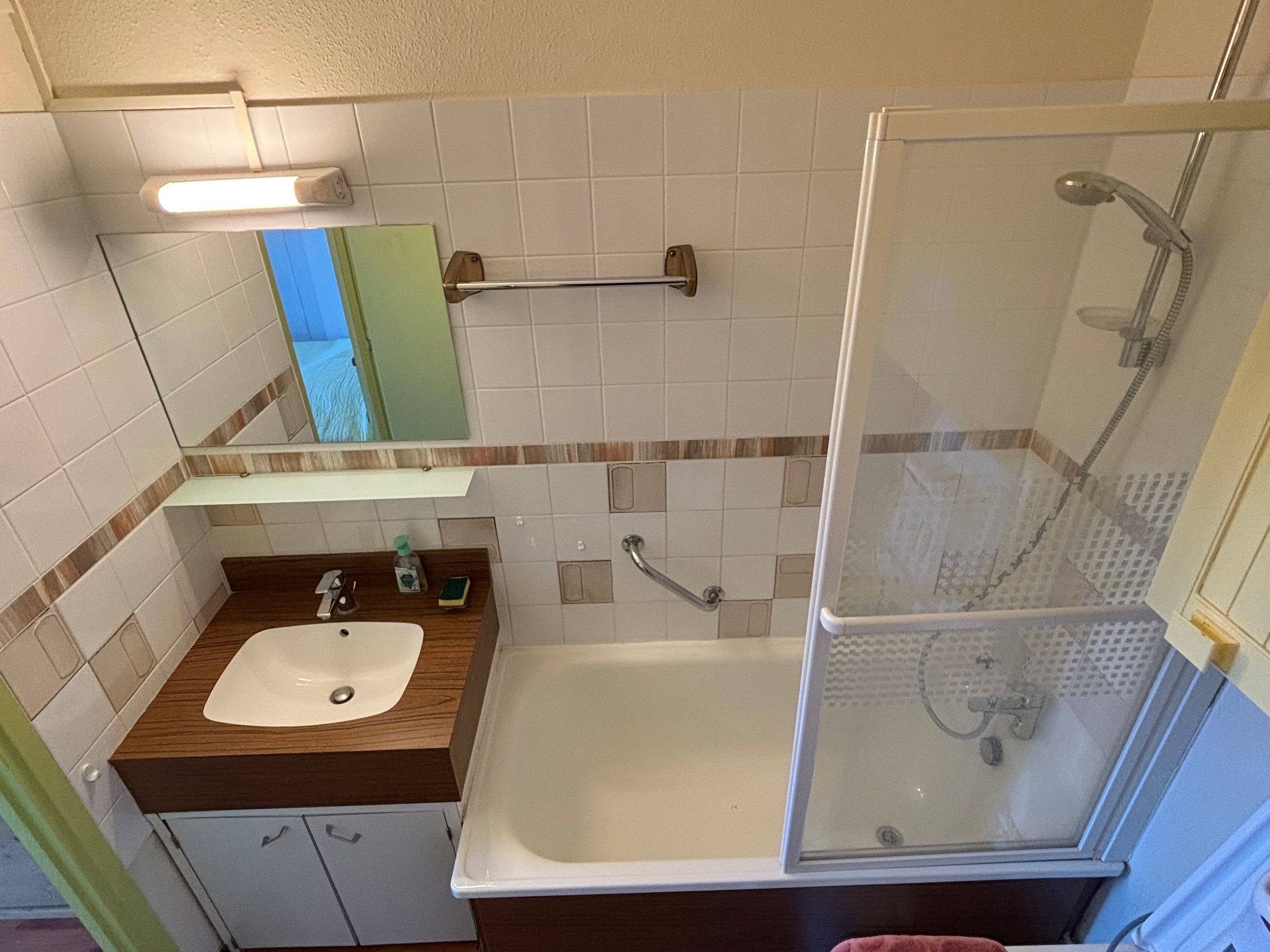 Une salle de bain équipée d’un lavabo, d’un miroir, d’un porte-serviettes et d’une douche à parois de verre.