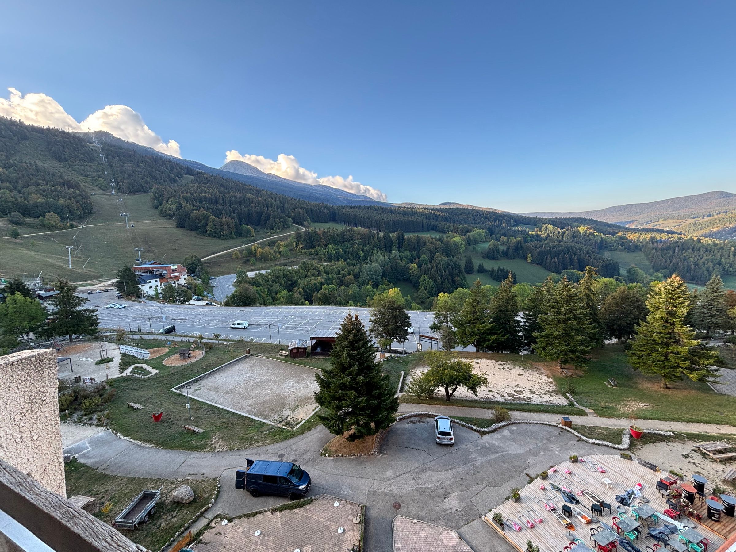 A mountainous landscape with a parking area, a small building, and a view of a valley.