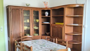 A dining area with a wooden table and chairs, a cabinet with glass doors, and a corner shelving unit. - T2 Apartment in Balcons de Villard, sleeps 4-6, near slopes (Villard-de-Lans)