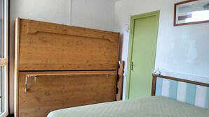 A room with a wooden wardrobe, a green door, and a bed with a quilted cover. - T2 Apartment in Balcons de Villard, sleeps 4-6, near slopes (Villard-de-Lans)