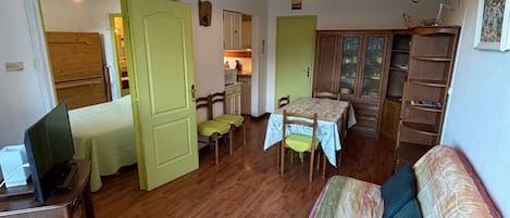 A compact living space with a dining area, kitchenette, and a sofa.