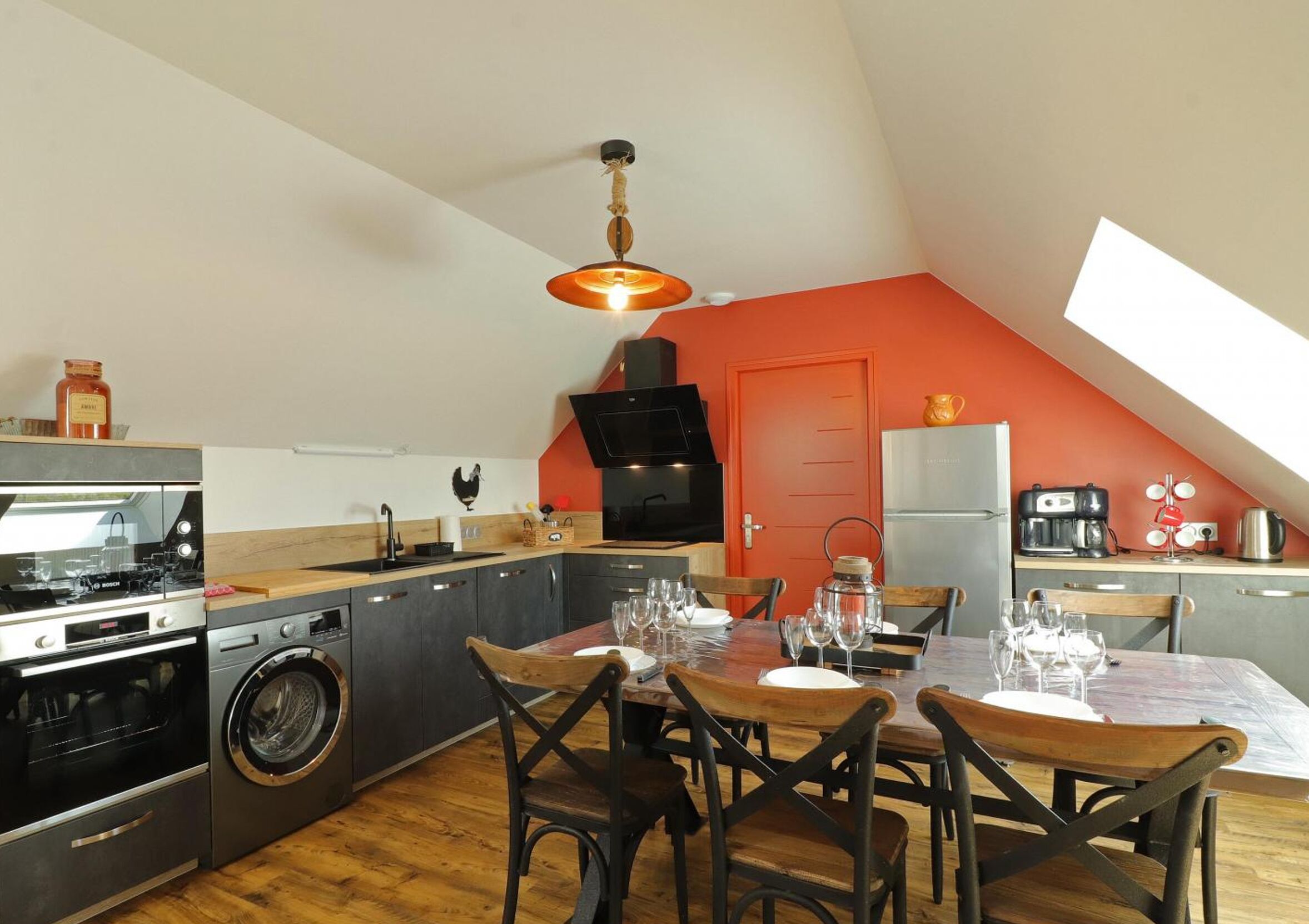 A compact kitchen with a dining area, a washing machine, and a built-in oven.
