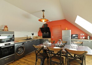 A compact kitchen with a dining area, a washing machine, and a built-in oven.